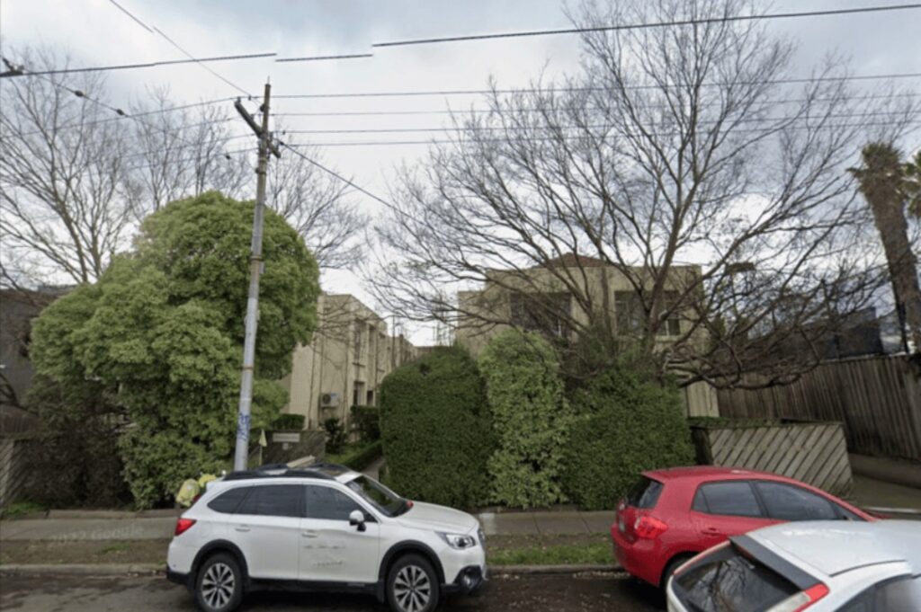 Street view of the exterior location of Lovehawkridge International Makeup Artist studio in St Kilda East, Melbourne, with parked cars and residential-style frontage surrounded by trees and hedges.